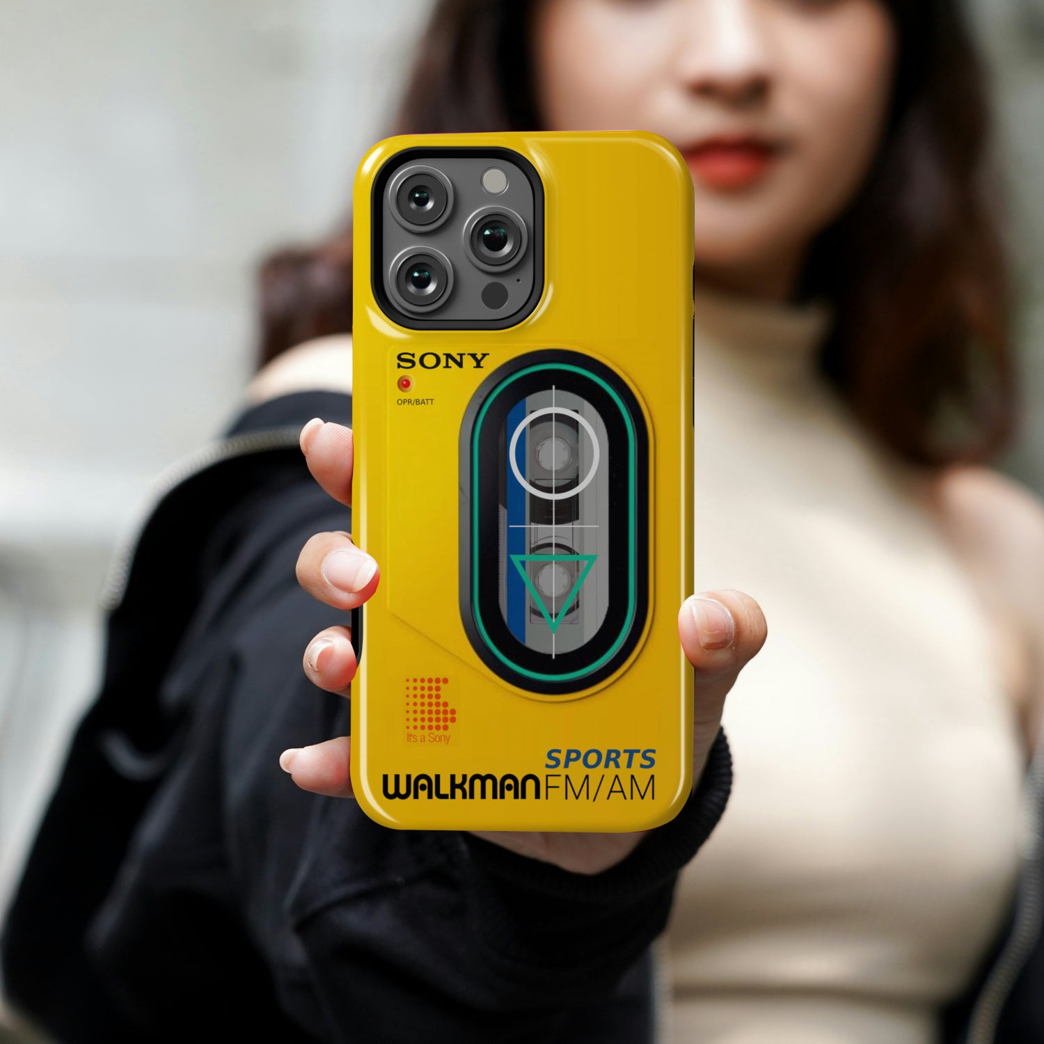 Person holding a yellow phone case with Sony Walkman design